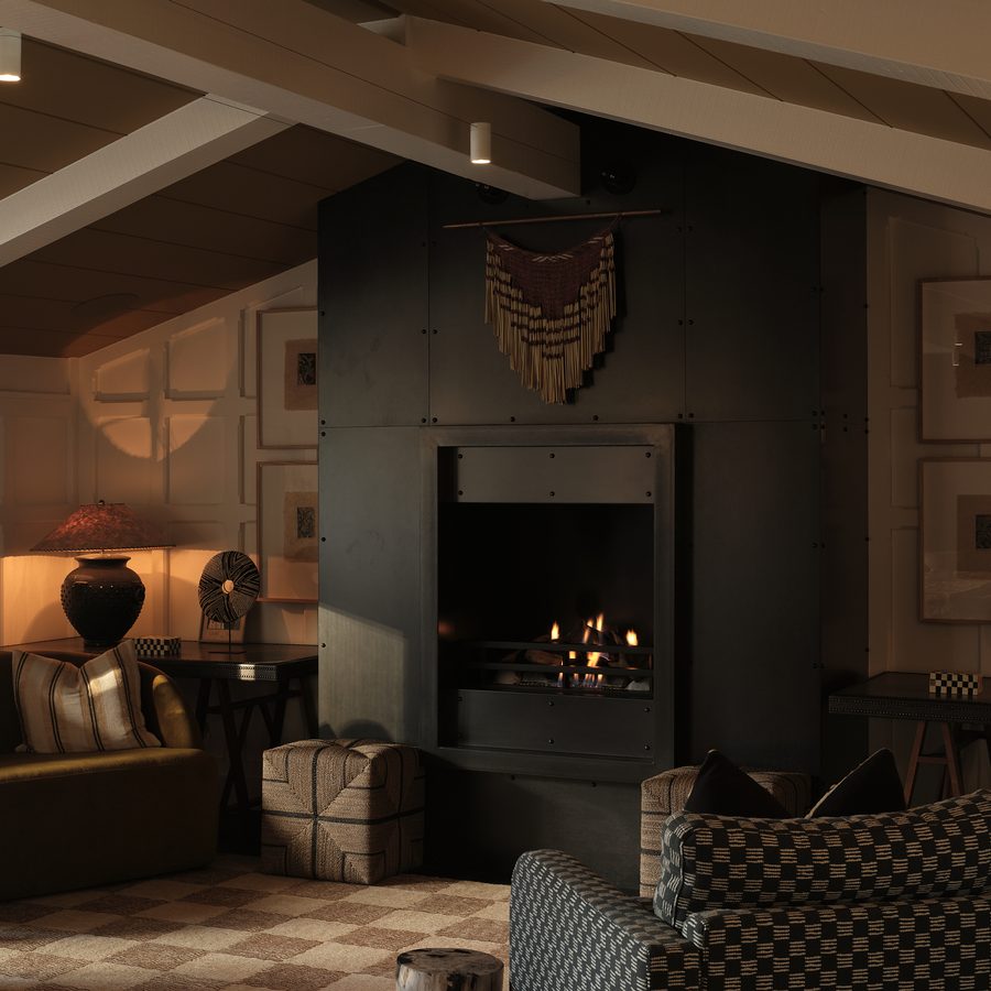 The lodge lounge with panelled walls, a timber-lined raked ceiling and a blackened steel fireplace