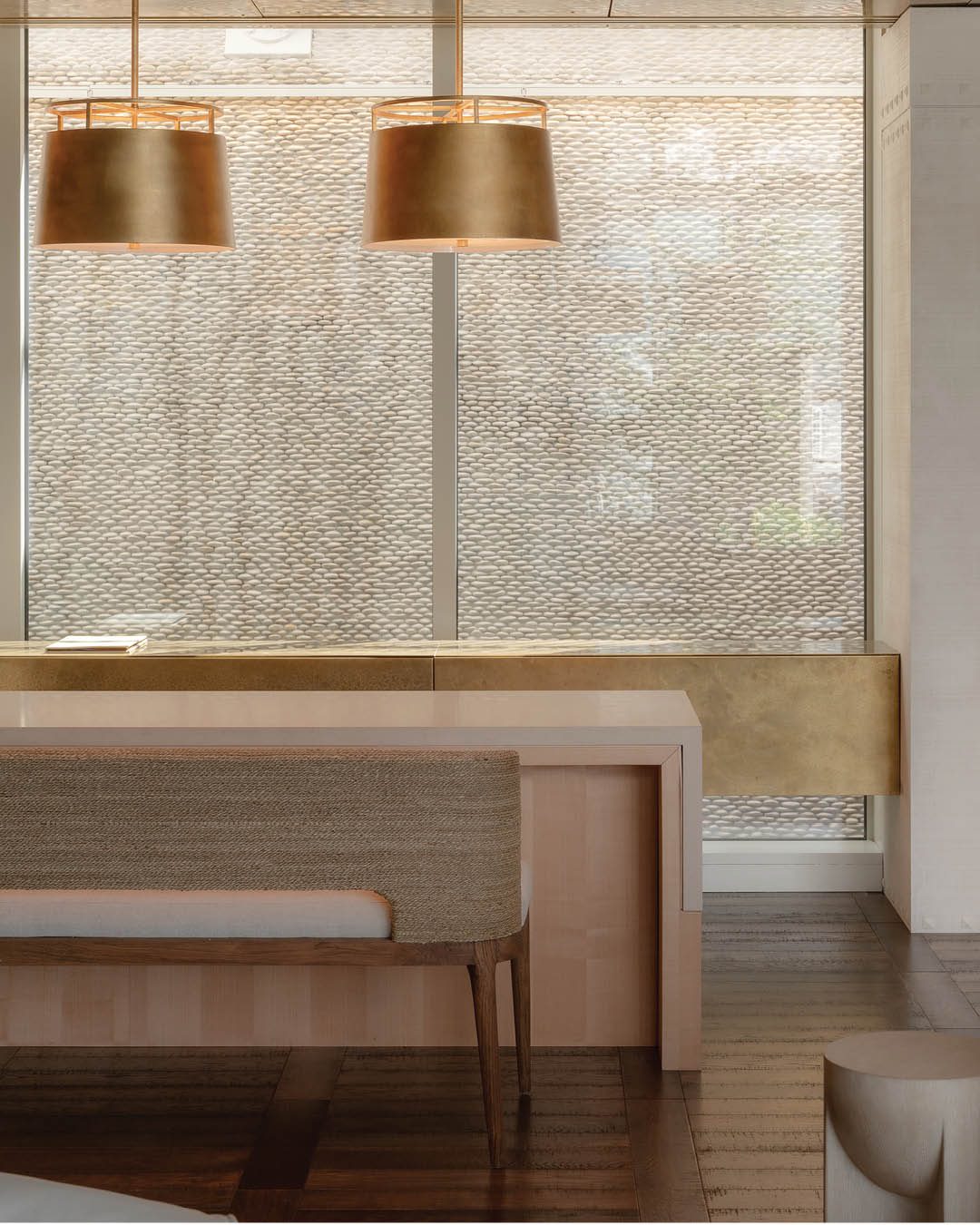 Dining space at Roki Collection with dark parquet flooring and brass pendant lights