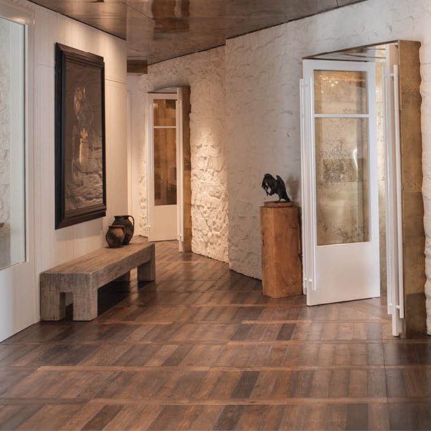 A gallery hallway with warm-toned timber plank flooring and white lime-washed stone walls