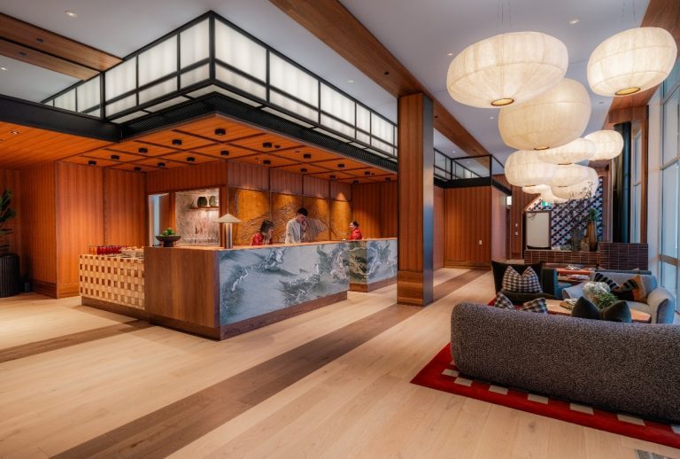 Hotel lobby and reception with wide plank pale oak floors, timber-lined walls and paper pendant lights